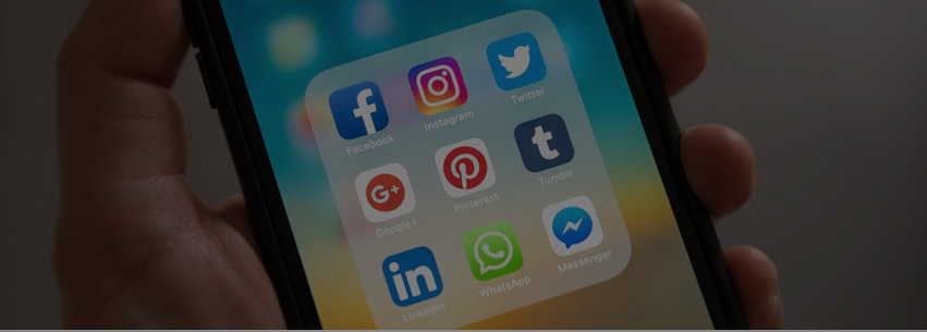 A hand holding a mobile phone that's displaying a collection of social media icons