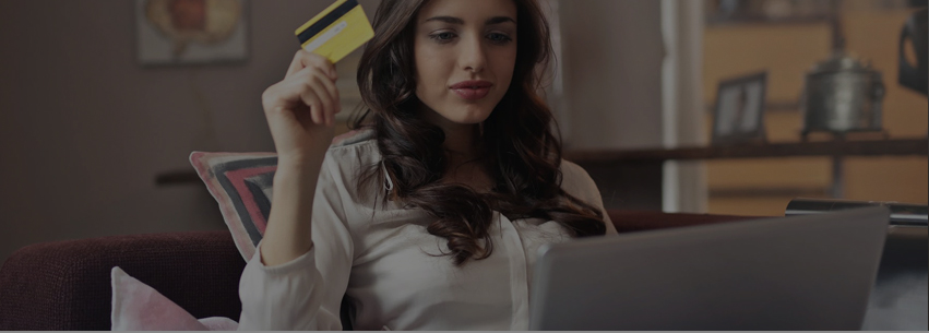 A woman looking at her computer holding a credit card